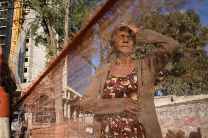 一名老妪站在她所住的贫民区与里约2016奥运公园工地之间的交界处。奥托多罗莫村（Vila Autodromo）这个离公园外缘不远的贫穷社区已预定拆除。 PHOT