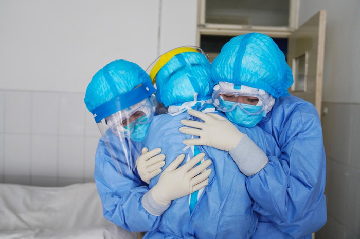 在中国山东省邹平市的一间医院里，医护人员在隔离病房内拥抱彼此。 PHOTOGRAPH BY STR/AFP VIA GETTY IMAGES