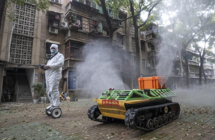 3月6号一辆坦克型机器人在中国武汉的街上喷洒消毒水。 专家在考量到人类健康后，现在不建议这样做。 PHOTOGRAPH BY BARCROFT MEDIA， G