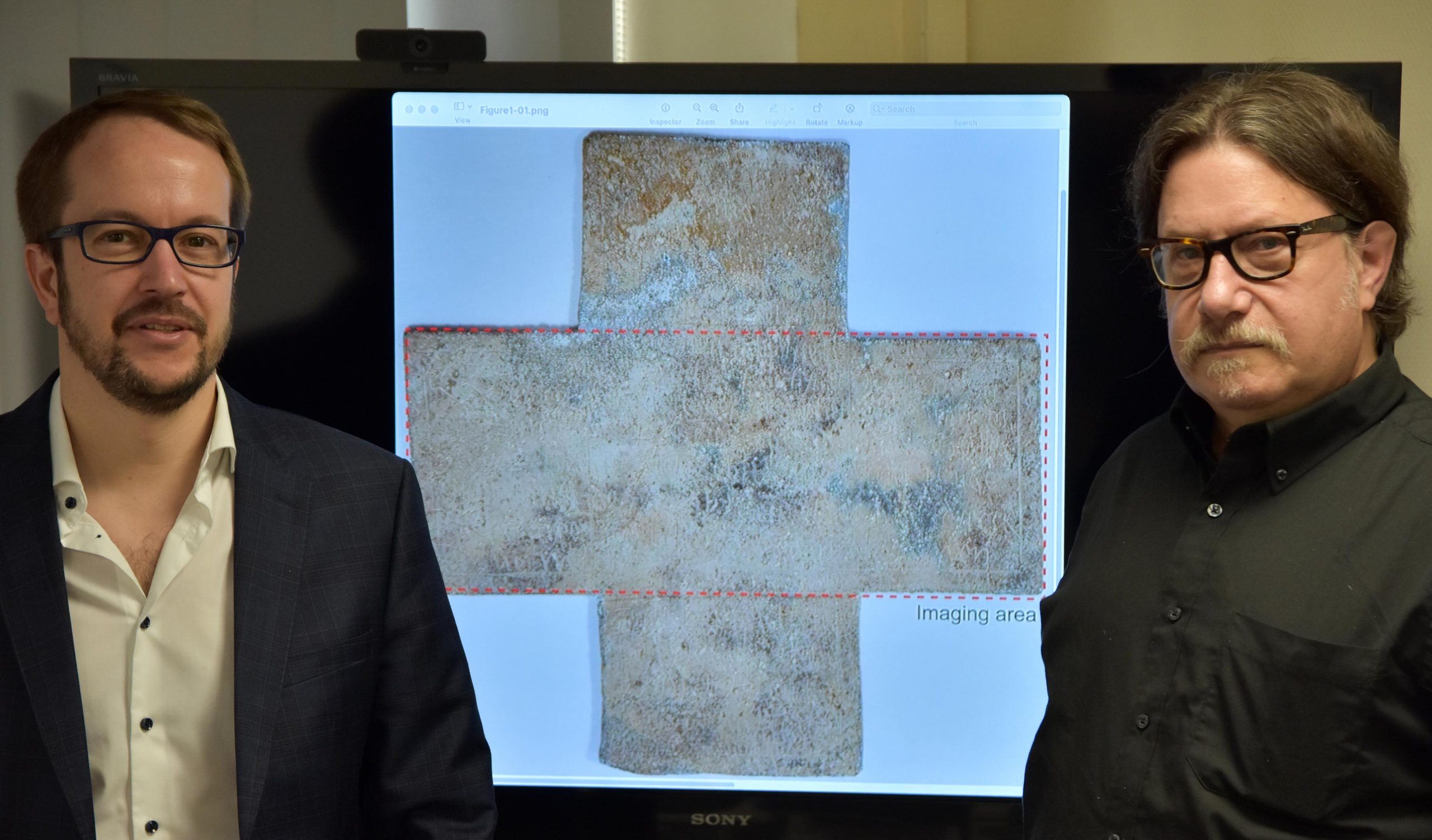 佐治亚理工学院教授David Citrin（右）和兼职教授Alexandre Locquet站在他们研究中使用的16世纪葬礼十字架的图像前。资料来源：佐治亚理工